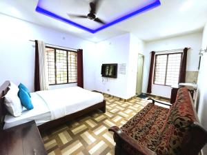 ein Schlafzimmer mit einem Bett, einem TV und einem Sofa in der Unterkunft Deluxe Residency in Kalpatta