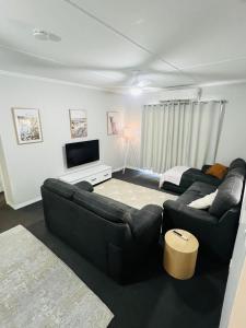 uma sala de estar com dois sofás e uma televisão em Bet you’ll love butler em Mount Isa