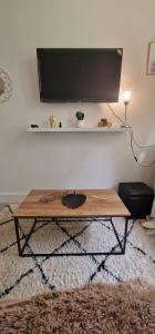 a coffee table in a living room with a flat screen tv at Appartement Jasmin 16ème in Paris