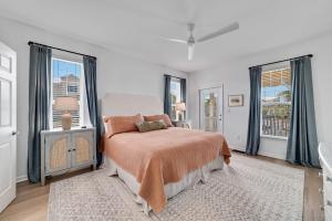 a white bedroom with a bed and two windows at The Sip at Sea in Gulf Shores