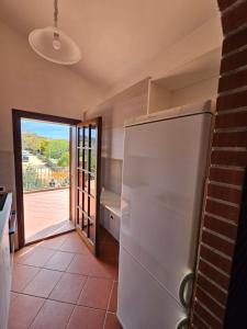 a kitchen with a refrigerator and a door to a patio at Arbatax, 200 metres from the beach: Apartment in villa with garden, 2 bedrooms in Àrbatax