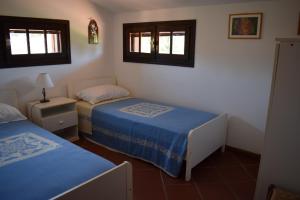 a bedroom with two beds and two windows at Arbatax, 200 metres from the beach: Apartment in villa with garden, 2 bedrooms in Àrbatax