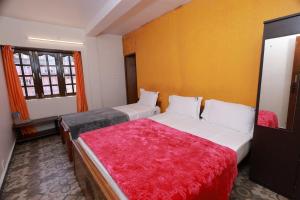 a bedroom with two beds and a red blanket at Seven Endue Cottages in Ooty