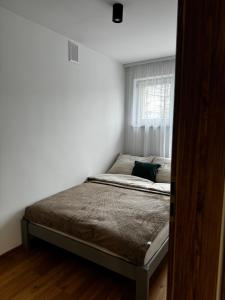 uma cama num quarto branco com uma janela em Apartament na Orkana em Rabka-Zdroj