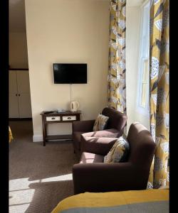 a living room with two chairs and a flat screen tv at Bonny Moor Hen in Stanhope