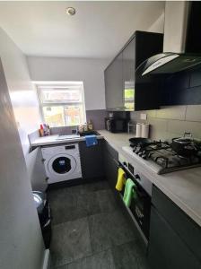 a kitchen with a stove and a washing machine at Lovely luxury one bedroom flat in London