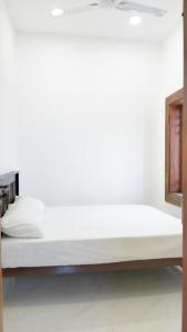 a bed in a room with a white wall at Rooms Trincomalee Low Price in Trincomalee