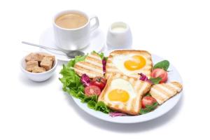 a plate of food with egg sandwiches and a cup of coffee at Hotel TU Casa (Stay near International Airport) in New Delhi