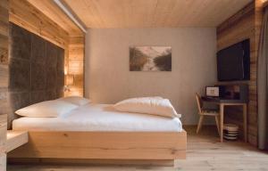 a bedroom with a bed with a desk and a television at Ruhehotel & Naturresort Rehbach - Adults only in Schattwald