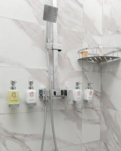 een douche in een badkamer met witte marmeren muren bij Hotel RA Lanka in Nuwara Eliya