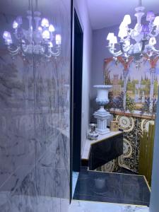 Rodigoにあるbristol palaceのバスルーム(シャンデリア付きのガラス張りのシャワー付)