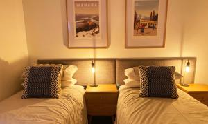 a bedroom with two beds and two lamps and posters at Burrows Hutch Wanaka in Albert Town