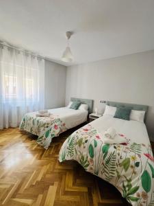 2 łóżka w pokoju z drewnianą podłogą w obiekcie VuT Las Almenas w mieście Avila