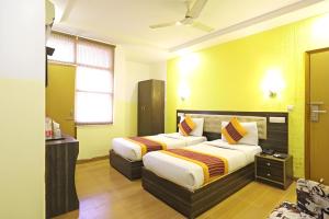 2 Betten in einem Hotelzimmer mit gelben Wänden in der Unterkunft Hotel King Plaza in Neu-Delhi