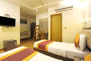 ein Hotelzimmer mit 2 Betten und einem TV in der Unterkunft Hotel King Plaza in Neu-Delhi
