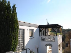 Dieses weiße Haus verfügt über einen Balkon mit einer Laube. in der Unterkunft Delightful Villa in Gerolstein with Private Garden in Gerolstein