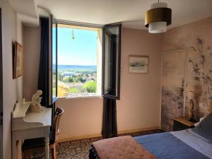 een slaapkamer met een raam, een bed en een bureau bij Maison de village panoramique in Châteauneuf-du-Pape
