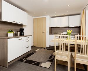 a kitchen with white cabinets and a table with chairs at Roslerhof in Inzing