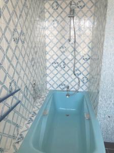 y baño con ducha y bañera azul. en Maison d'hôtes La Doucelle en Lignieres-Orgeres