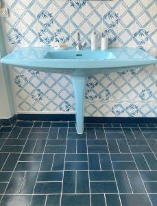 een blauwe wastafel in een badkamer met een tegelvloer bij Maison d'hôtes La Doucelle in Lignieres-Orgeres