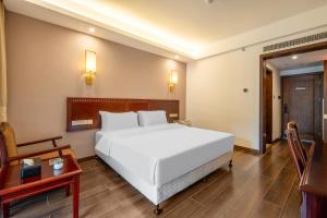 ein Schlafzimmer mit einem großen weißen Bett und einem Tisch in der Unterkunft Hunan New Pipaxi Hotel in Zhangjiajie