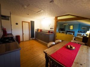 a kitchen and living room with a wooden table with a red cloth at Pirnmill Home with a view in Pirnmill