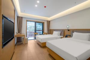 a hotel room with two beds and a flat screen tv at Hunan New Pipaxi Hotel in Zhangjiajie
