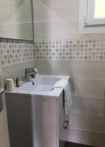 een witte badkamer met een wastafel en een spiegel bij Studios - Location de vacances Le Trécelin in Plévenon