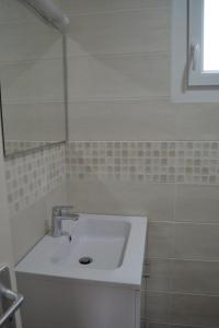 een badkamer met een witte wastafel en een spiegel bij Studios - Location de vacances Le Trécelin in Plévenon +23 foto's