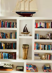uma estante de livros brancos com livros e um barco nela em Alkyon Hotel em Parikia