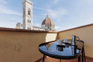 uma mesa de vidro numa varanda com uma torre do relógio em Duomo View Apartment em Florença