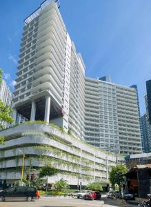 マニラにあるLush Residences Makatiの大きな白い建物とその前に駐車された車