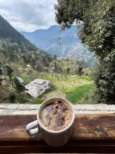 uma chávena de café sentada no parapeito da janela em MOZO Inn&Cafe Jibhi em Banjār