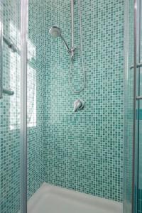 y baño con ducha y paredes de azulejos verdes. en House Rene, en Agerola