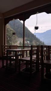 uma mesa e bancos num quarto com vista em MOZO Inn&Cafe Jibhi em Banjār