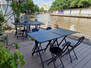 a row of tables and chairs next to a river at V Space CAPSULE CAFE MELAKA in Malacca
