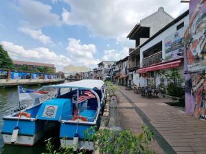 een blauwe boot aangemeerd naast een kanaal bij V Space CAPSULE CAFE MELAKA in Melaka