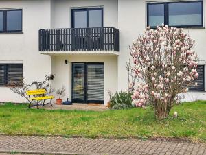 um banco amarelo em frente a uma casa com uma árvore florida em Fuchs und Hase em Illingen
