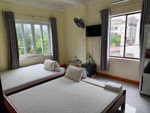 2 letti in una camera con 2 finestre di View Nhat Le Beach Hotel a Dong Hoi