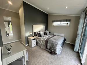 a bedroom with a bed and a desk in it at Waterside Retreat Heron Lakes Nr Beverley in Beverley