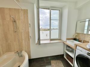 La salle de bains est pourvue d'une baignoire, d'un lavabo et d'une fenêtre. dans l'établissement GITE LA VUE LOIRE Maison, à Saint-Denis-de-l'Hôtel