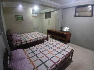 two beds in a room with a desk and a bed at Hotel Pelangi HS in Ngabean