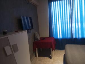 um pequeno quarto com uma mesa vermelha e uma televisão em VILLA BELLA VITA HAMMAMET em Hammamet Sud