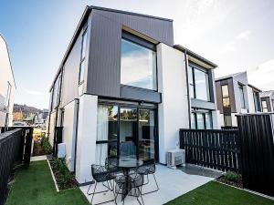 uma casa com um pátio com uma mesa e cadeiras em Burrows Hutch Wanaka em Albert Town