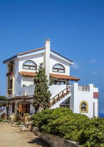 a white building with a tree in front of it at Iliatoras in Agia Pelagia