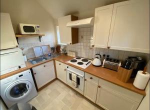 a kitchen with a washing machine and a washer at A charming cottage in a beautiful setting. in Hungerford