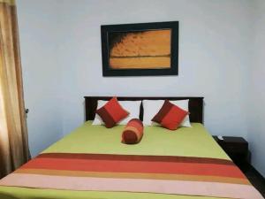 a bedroom with a bed with red and orange pillows at The European Gate - Anuradhapura in Anuradhapura