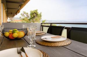 a wooden table with plates and glasses and a bowl of food at Sea front Elegant Apartment in Kalandra