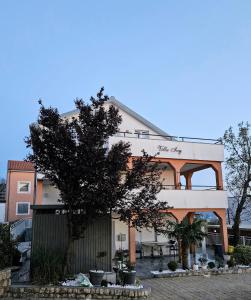 un edificio con un árbol delante de él en Apartments Lujić, en Crikvenica