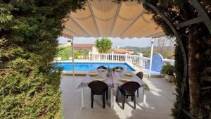 una mesa y sillas en un patio junto a la piscina en El Refugio, en Turís